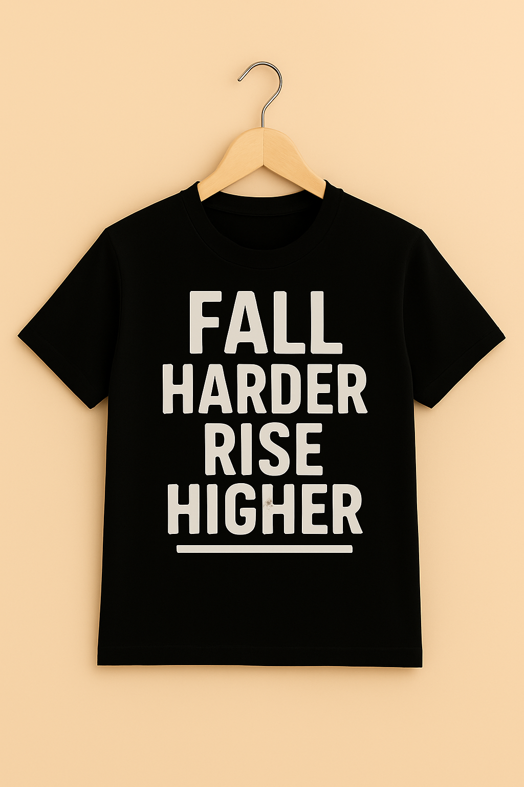 Black t-shirt with 'Fall Harder Rise Higher' text with hanger on a beige background