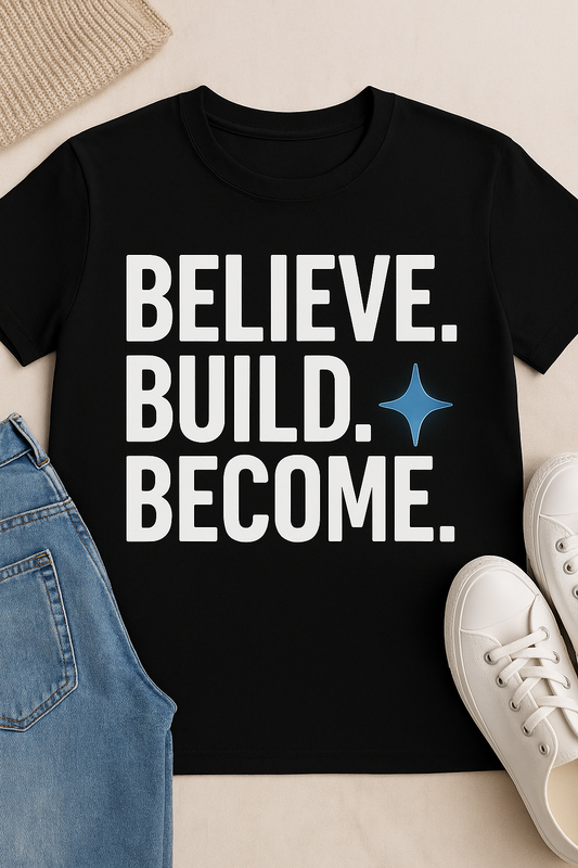 Black t-shirt with 'BELIEVE. BUILD. BECOME.' text on a beige surface with jeans and sneakers.