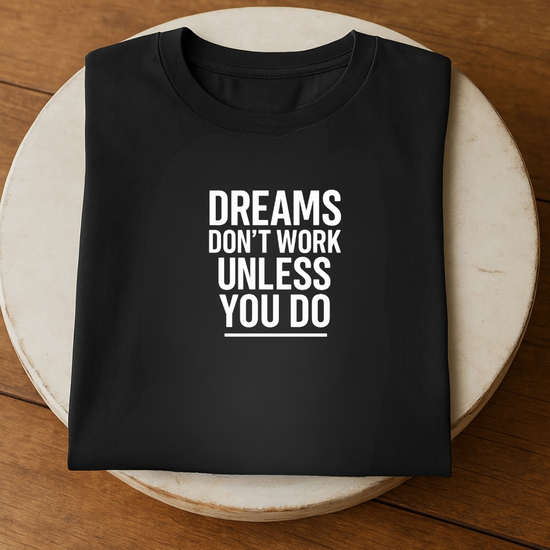Flat lay of black t-shirt on round table with Dreams Don’t Work Unless You Do typography