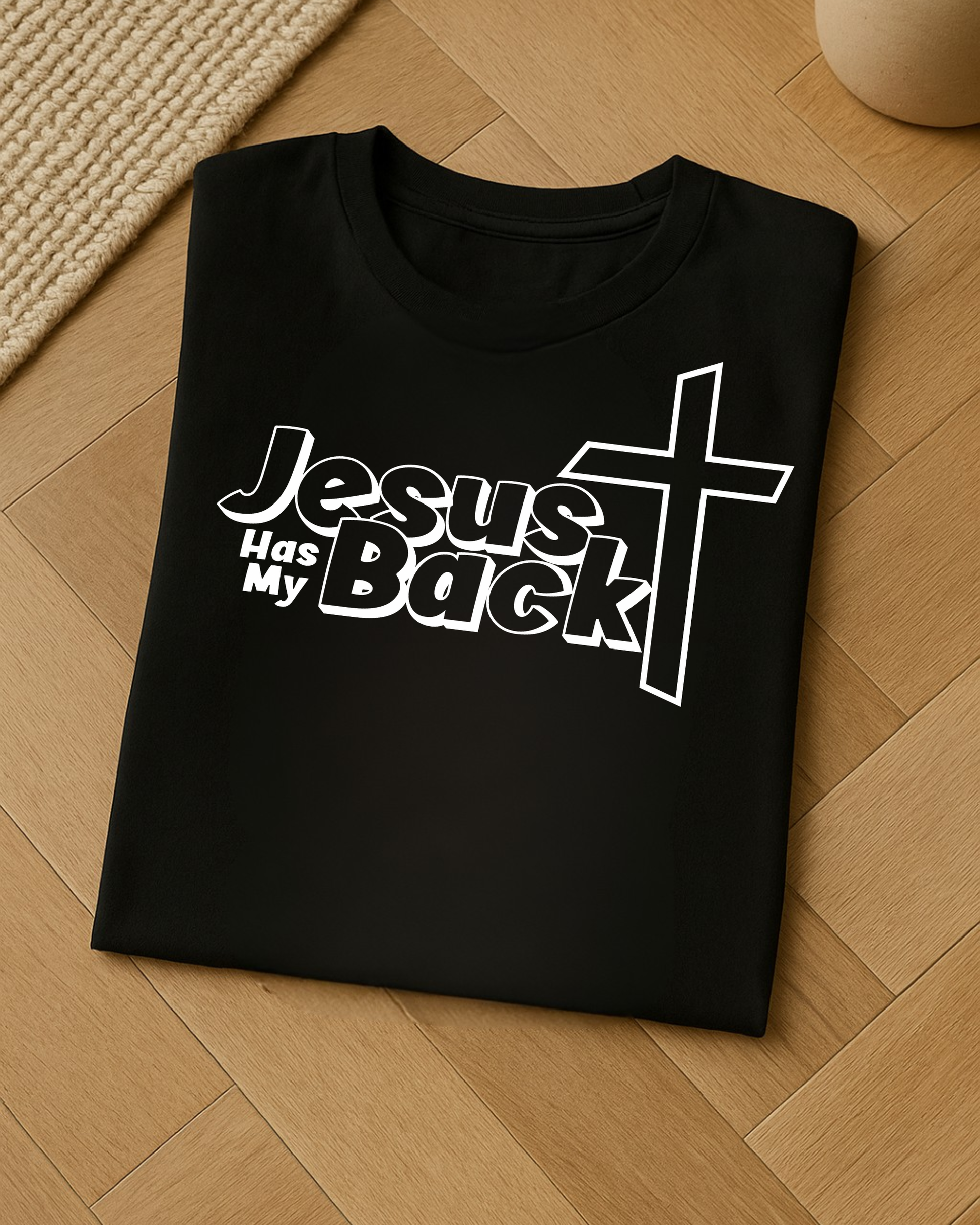 Folded black “Jesus Has My Back” Christian T-shirt on wooden floor