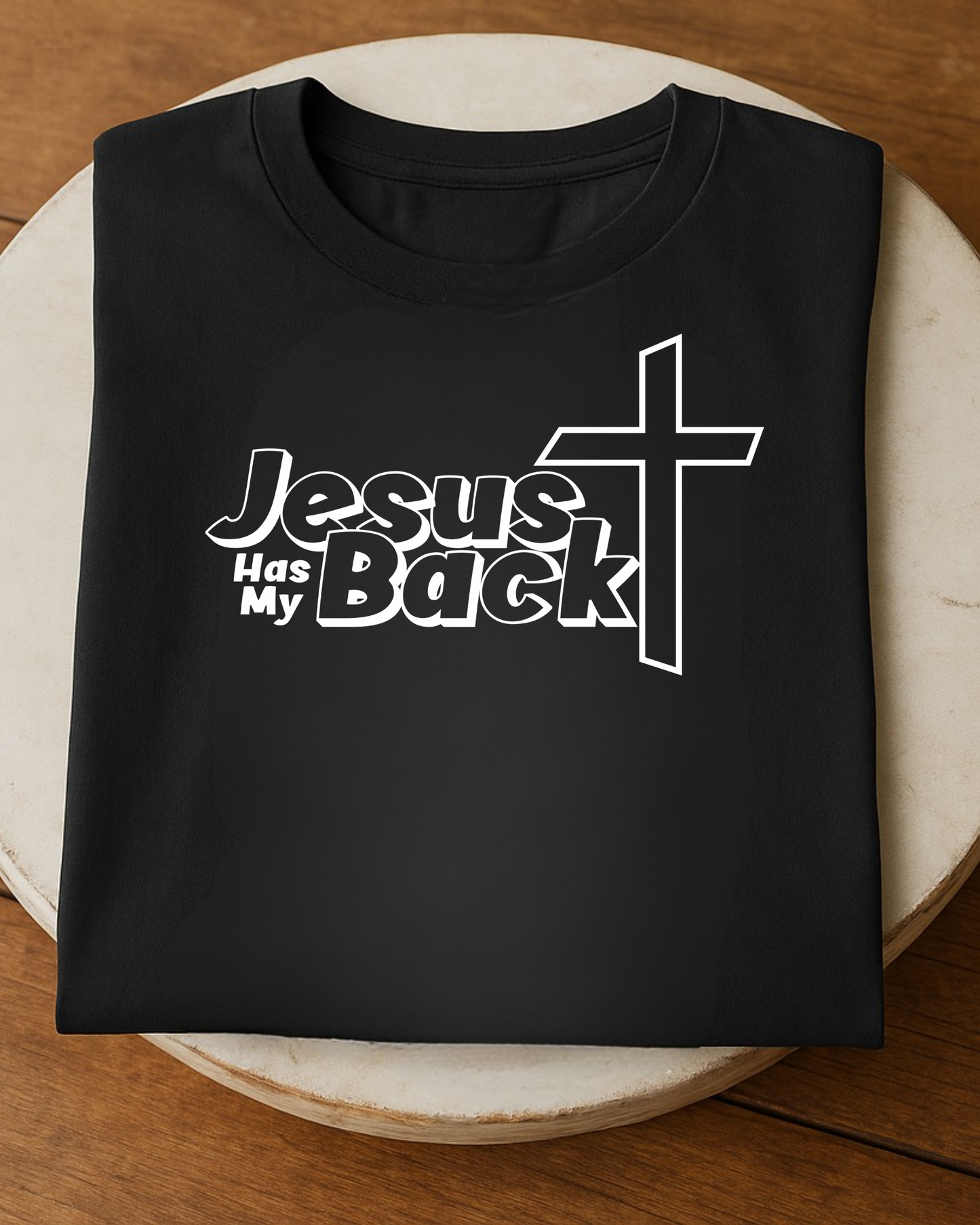 Folded black “Jesus Has My Back” Christian T-shirt on round table
