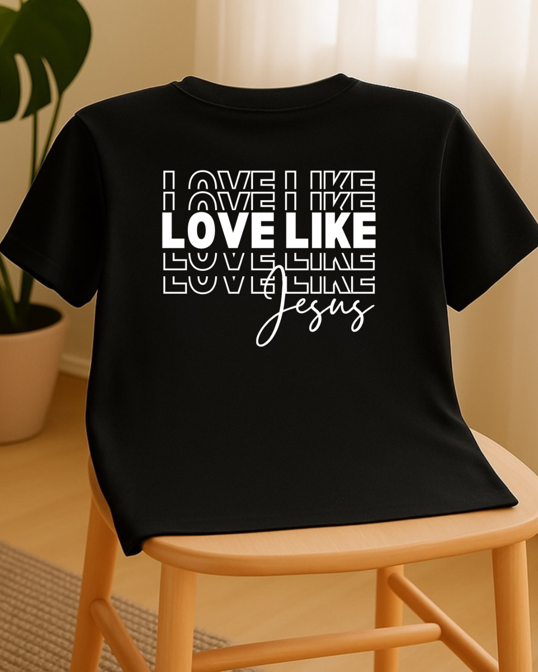 Love Like Jesus Christian T-shirt displayed on chair in lifestyle home setting