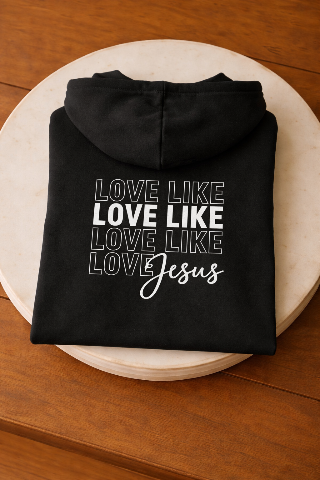 Folded black Love Like Jesus Christian hoodie with bold faith typography
