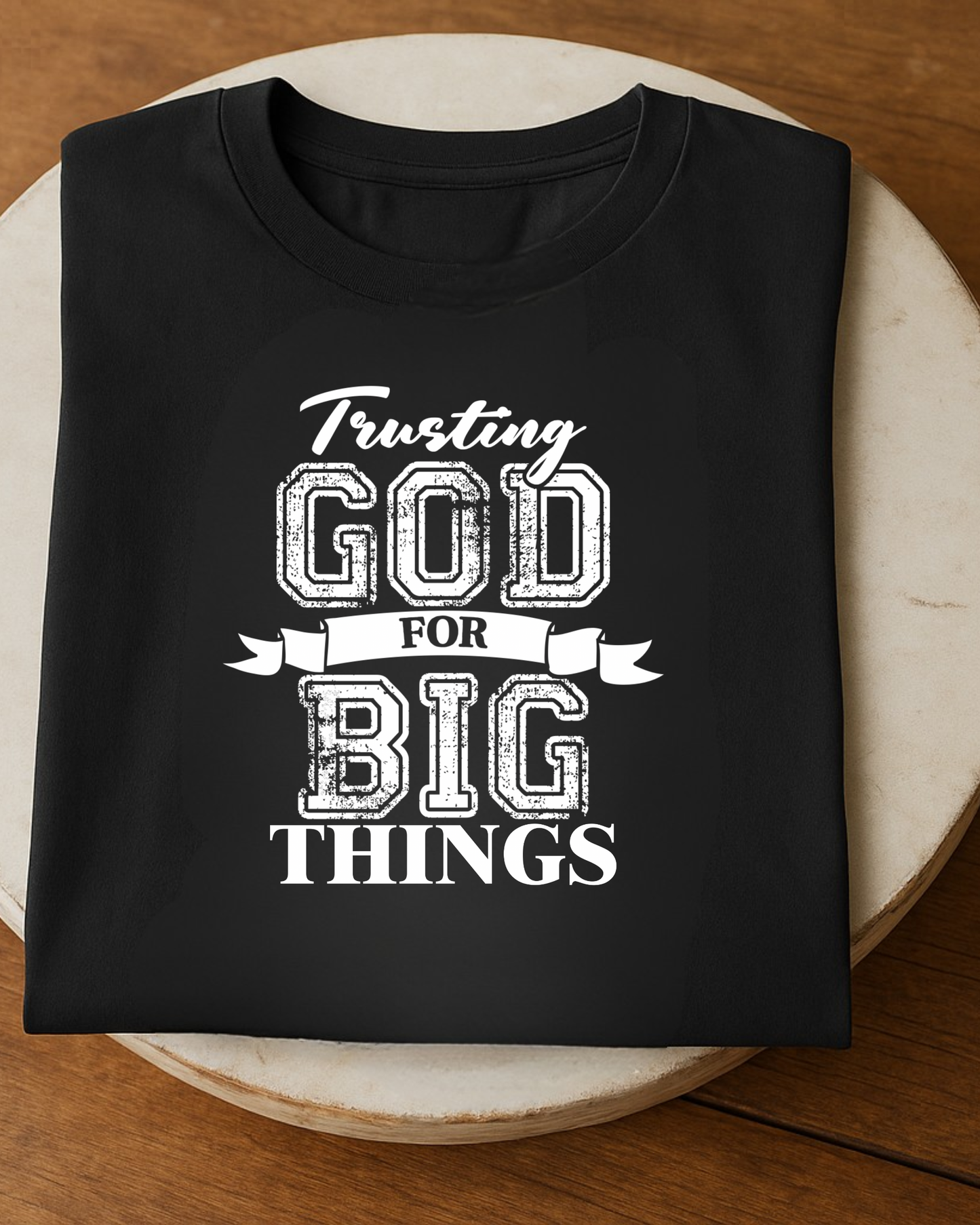 Folded black faith t-shirt displaying trusting God for big things Christian typography design