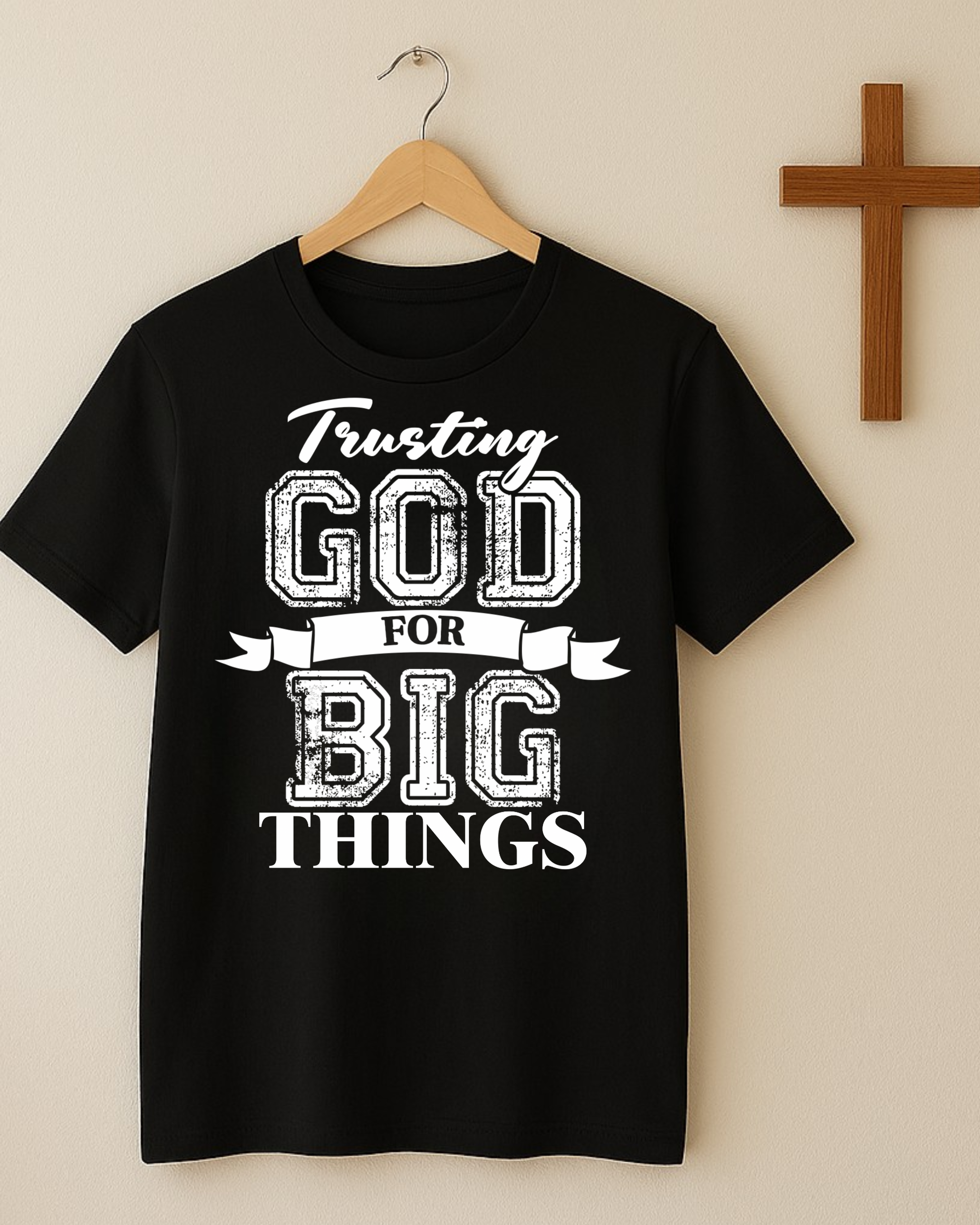 Christian shirt hanging on wooden hanger beside cross wall decor with trusting God for big things quote