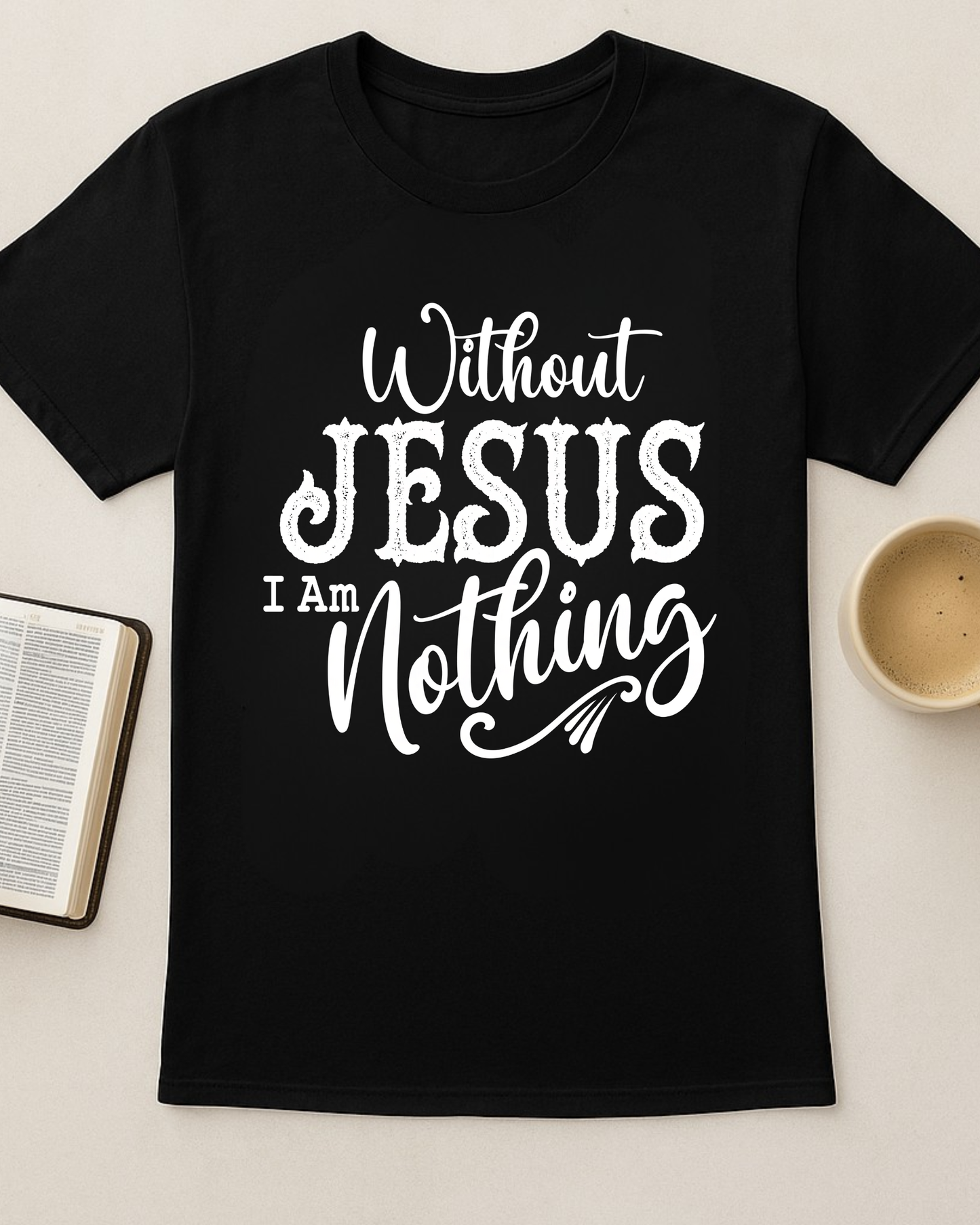 Black Christian T-shirt featuring the quote “Without Jesus I Am Nothing” displayed flat lay next to a Bible and coffee mug.